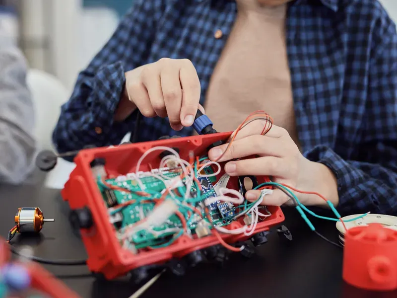 Hands connecting wires and electronics in a prototype assembly