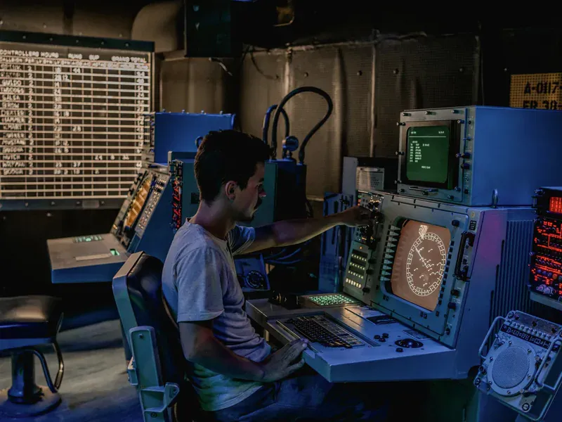 Operator working at an industrial electronic control station used for monitored data recording