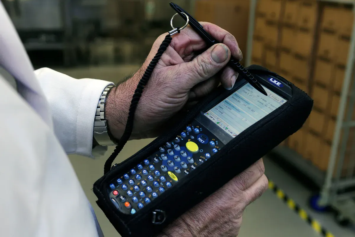 Warehouse worker using an industrial barcode terminal for inventory identity checks