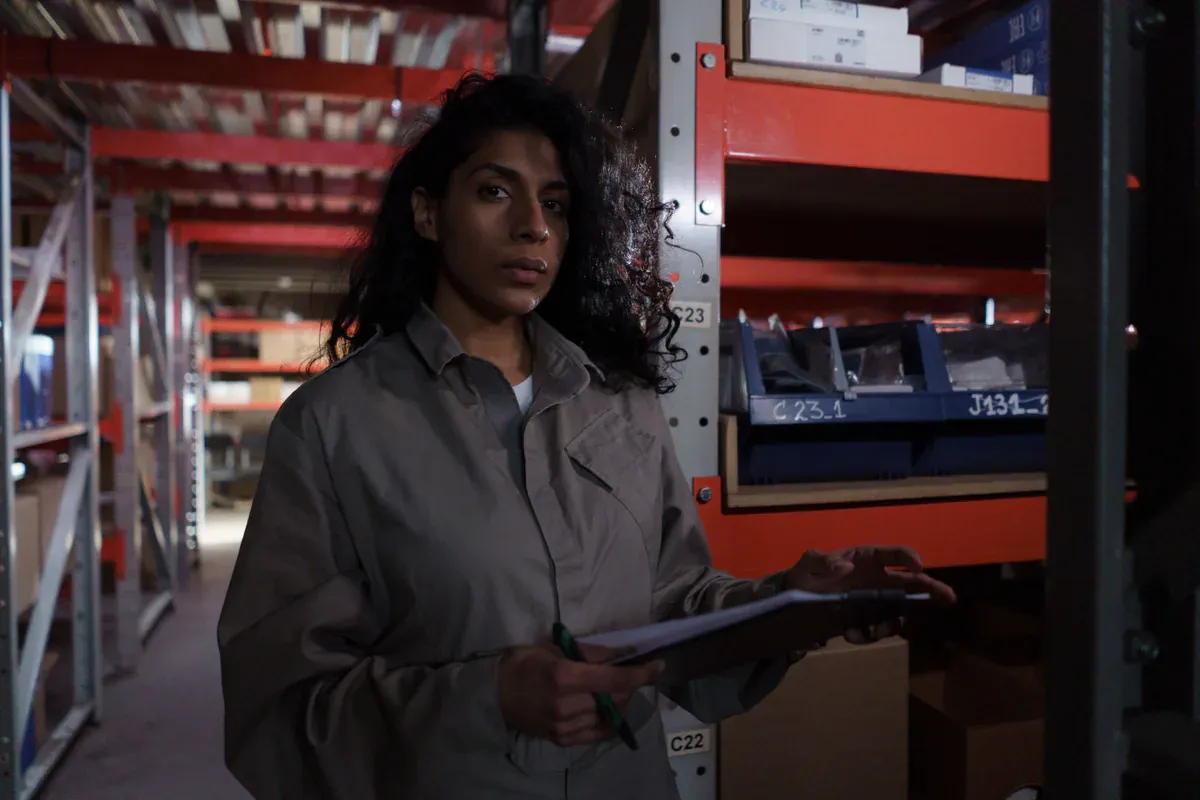 Warehouse specialist checking stock against a clipboard inventory record