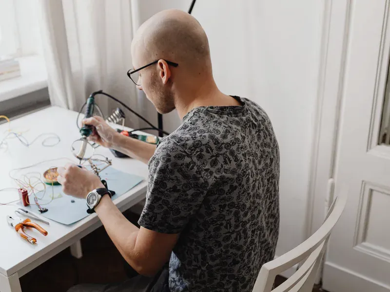 Technician working with circuit boards and tools at an electronics desk