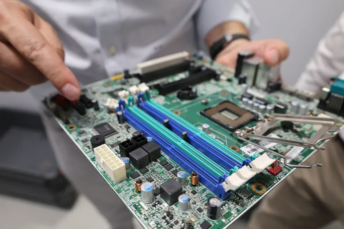 Technician handling a populated circuit board during electronics inspection