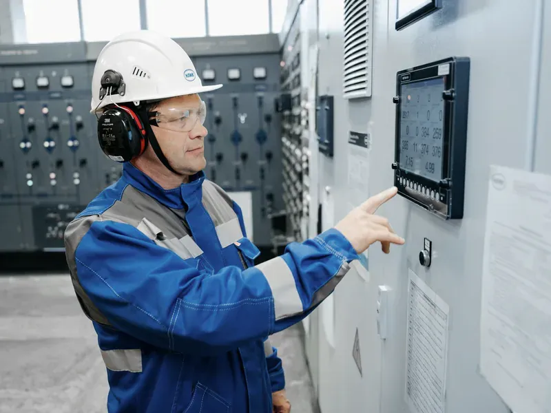 Technician using a meter while checking an industrial control panel