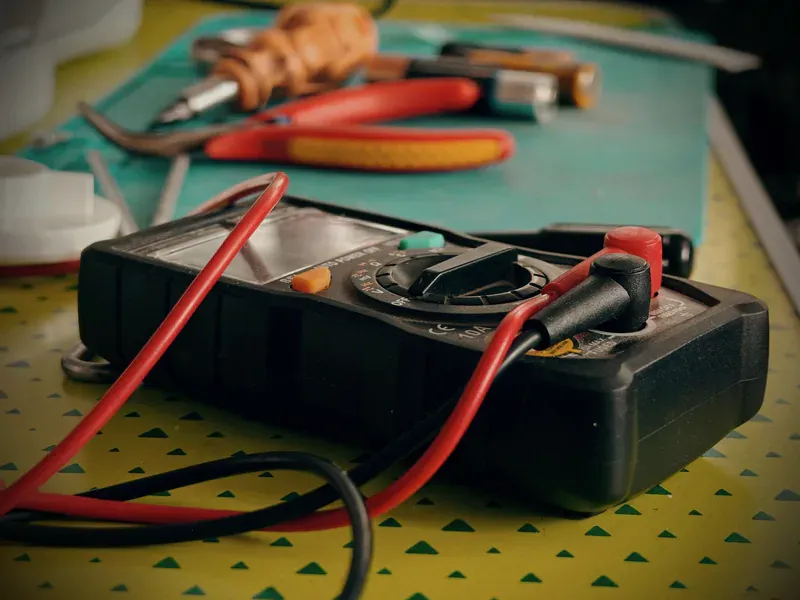 Multimeter and electronics tools on a workbench used to verify defined circuit test conditions