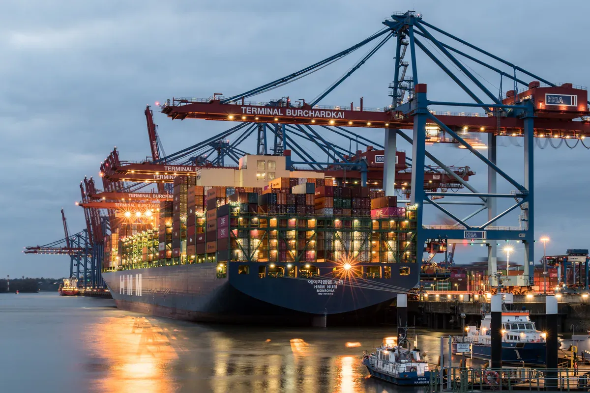 Container ship and cargo cranes operating at a commercial seaport