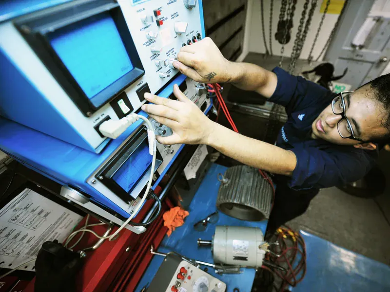 Technician using an oscilloscope to test an electric motor