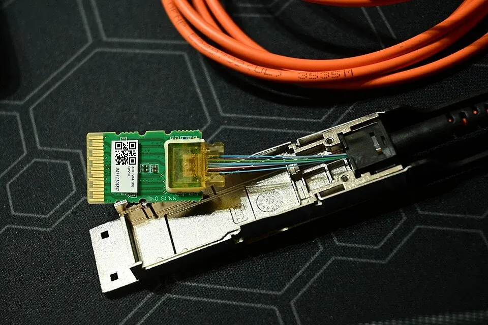 An opened QSFP optical transceiver showing its circuit board and internal fiber connections