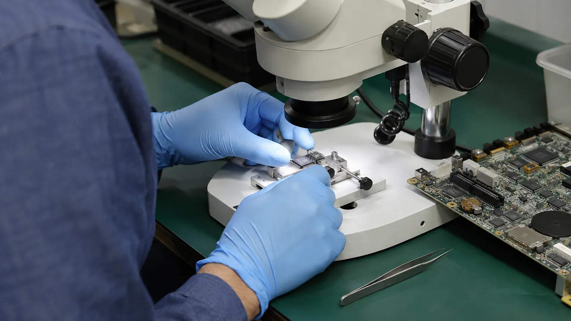 Quality inspector examining an integrated circuit under a laboratory microscope
