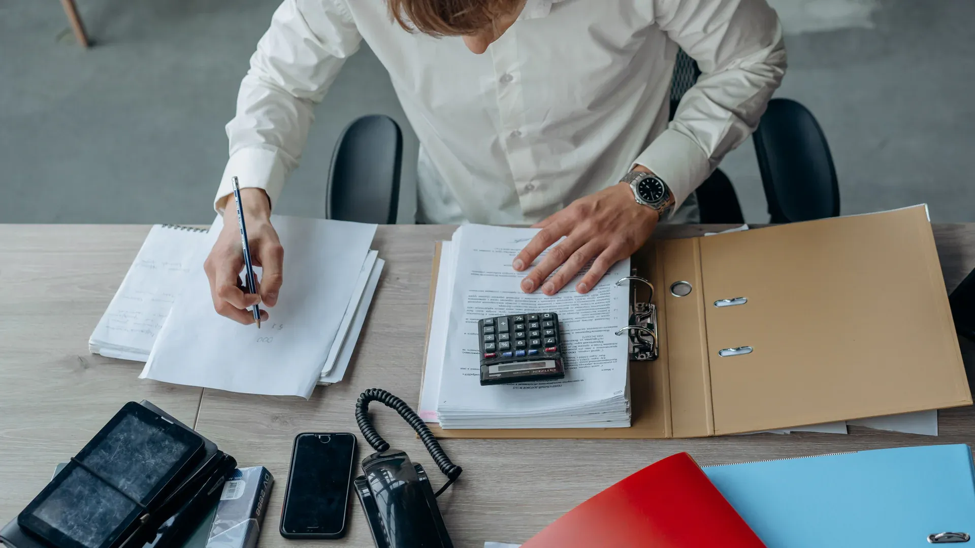Procurement specialist reviewing supplier quotes and calculations at a desk