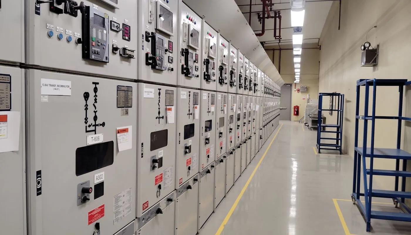 Industrial electrical control room with rows of switchgear and control panels