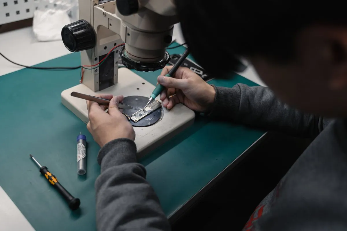 Technician examining a circuit board through a stereo microscope